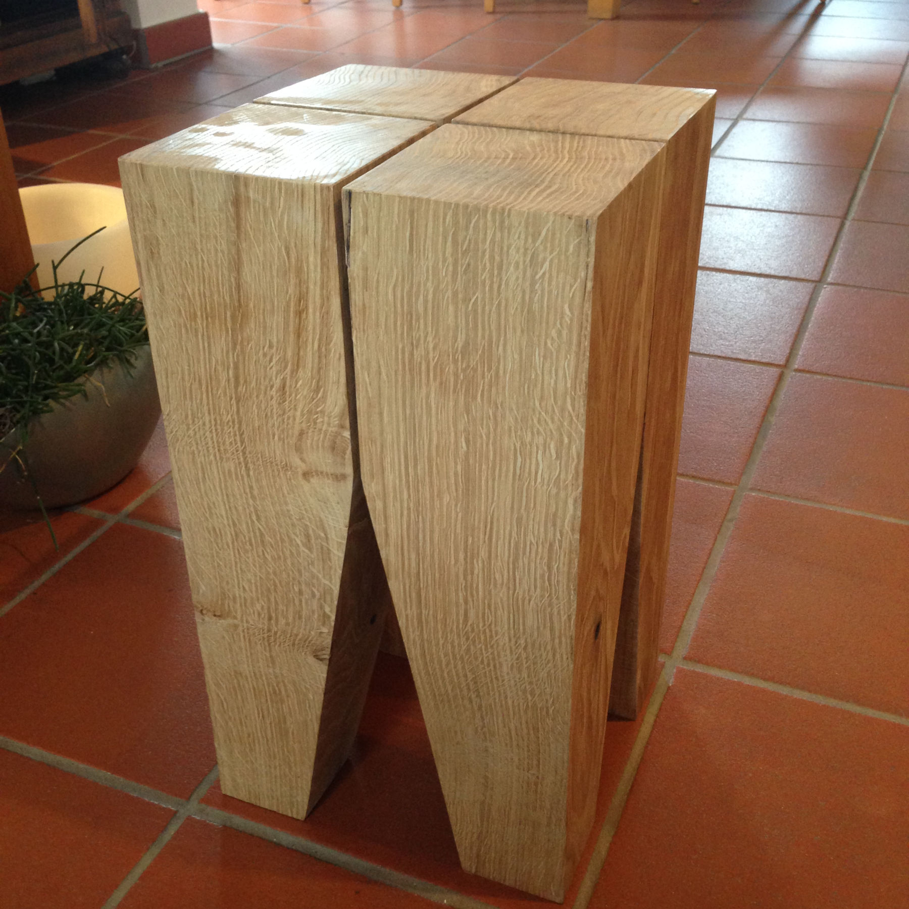 Sgabello artigianale composto da quattro colonne identiche in rovere massiccio con piani in testa visibili e giunzioni verticali di precisione.